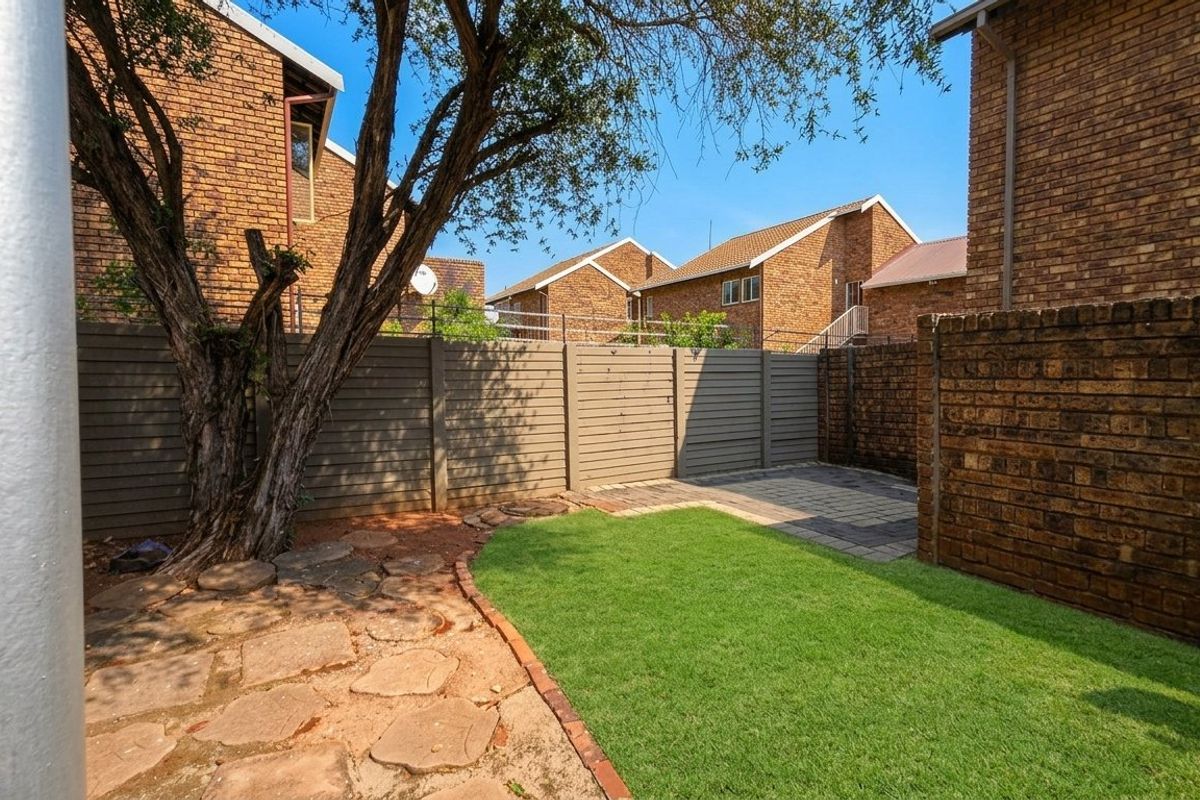 A private rear garden featuring a small lawn, paved patio area, and brick boundary walls, providing a functional outdoor space.