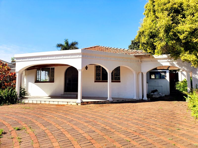 Front elevation of a house featuring a covered arched veranda, brick paved driveway, and classic architectural detailing.