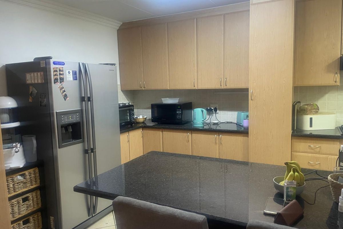 A functional kitchen featuring light wood-finish cabinetry, dark granite countertops, and a central island, providing ample storage and workspace.