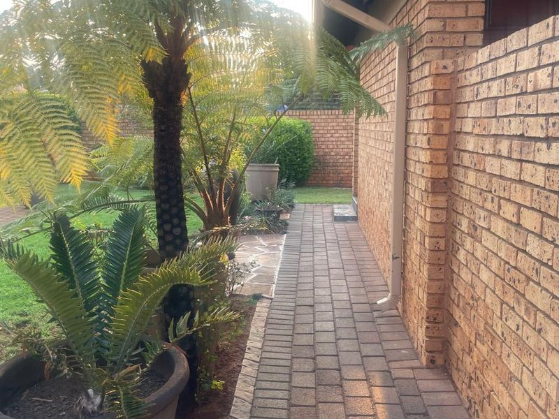 A side walkway featuring brick paving alongside the townhouse exterior wall, leading towards the rear garden area.