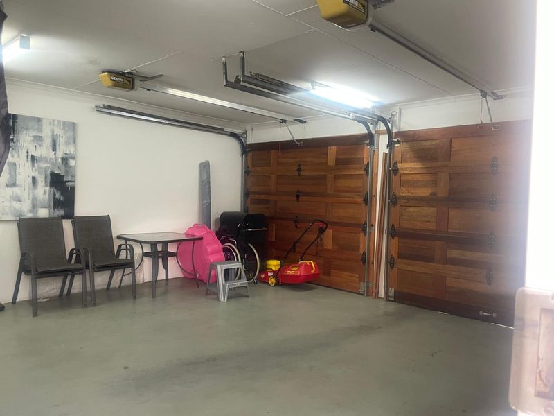 Spacious double garage featuring automated wooden doors, durable epoxy flooring, and integrated lighting, providing secure parking and additional storage space.