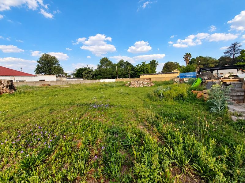 A vacant residential plot featuring open grass areas and perimeter boundary walls, offering a blank canvas for future development.