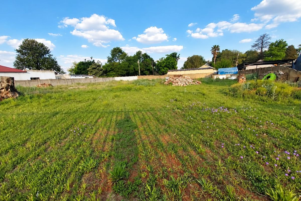A vacant residential plot featuring a grassy area enclosed by perimeter walls, offering a blank canvas for future development.