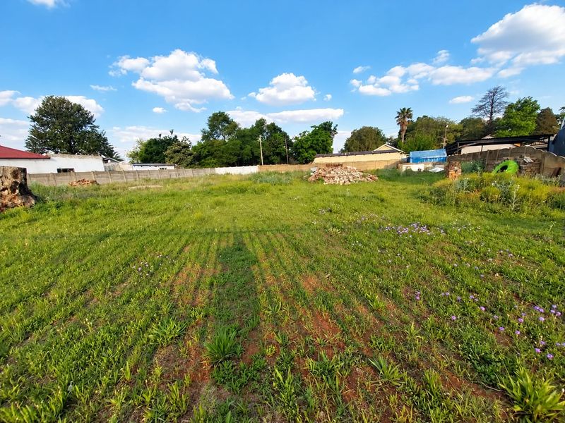 A vacant residential plot featuring a grassy area enclosed by perimeter walls, offering a blank canvas for future development.