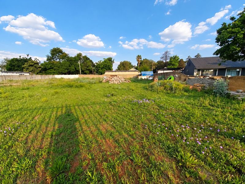 A vacant residential plot featuring a grassy area enclosed by a precast concrete boundary wall, suitable for future development.
