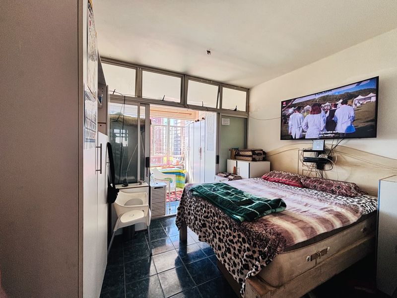Bedroom featuring tiled flooring, built-in wardrobe, and direct access to a balcony through sliding glass doors with transom windows.