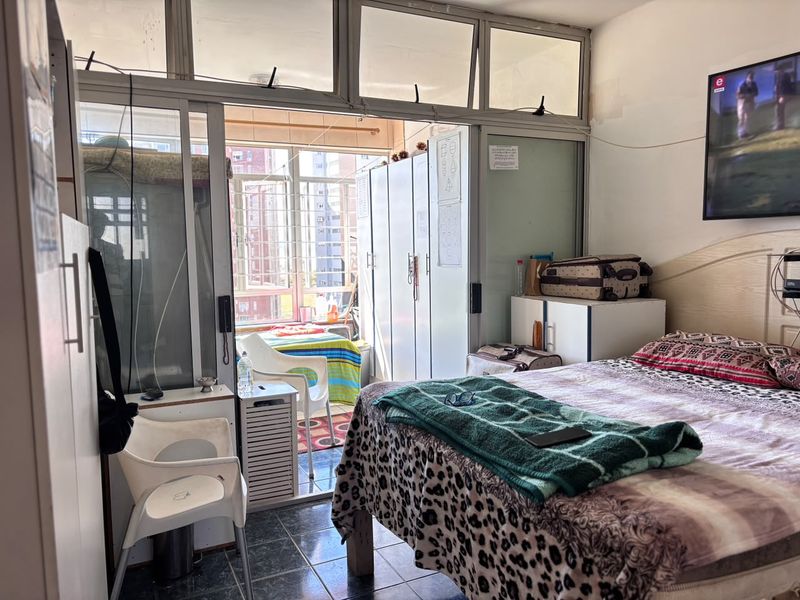 Bedroom featuring tiled flooring, built-in cupboards, and aluminium sliding doors leading to an enclosed balcony area.