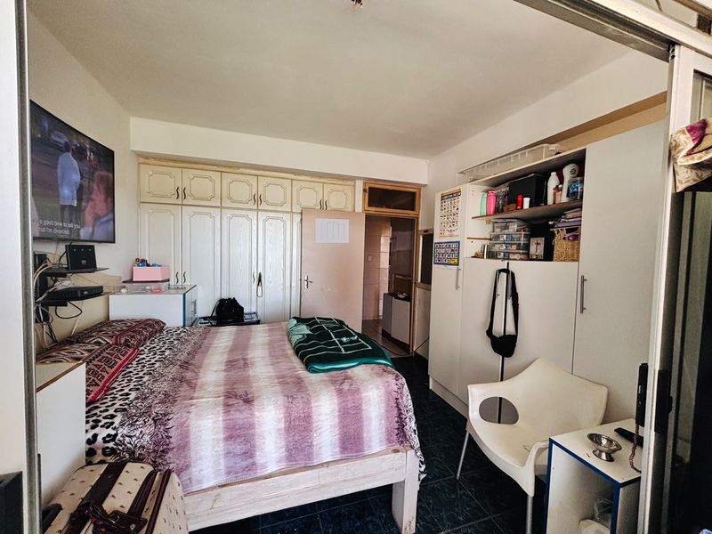 A bedroom featuring built-in cupboards and tiled flooring, offering functional storage space.