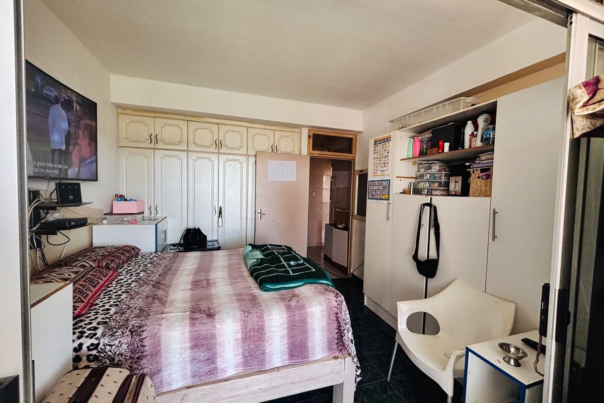 A bedroom featuring built-in cupboards and tiled flooring, offering functional storage space.