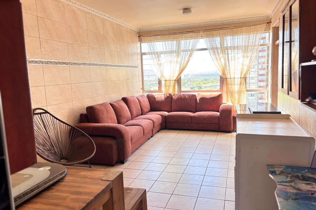 A living room featuring tiled flooring, decorative wall tiling, and a large window providing natural light and an urban view.