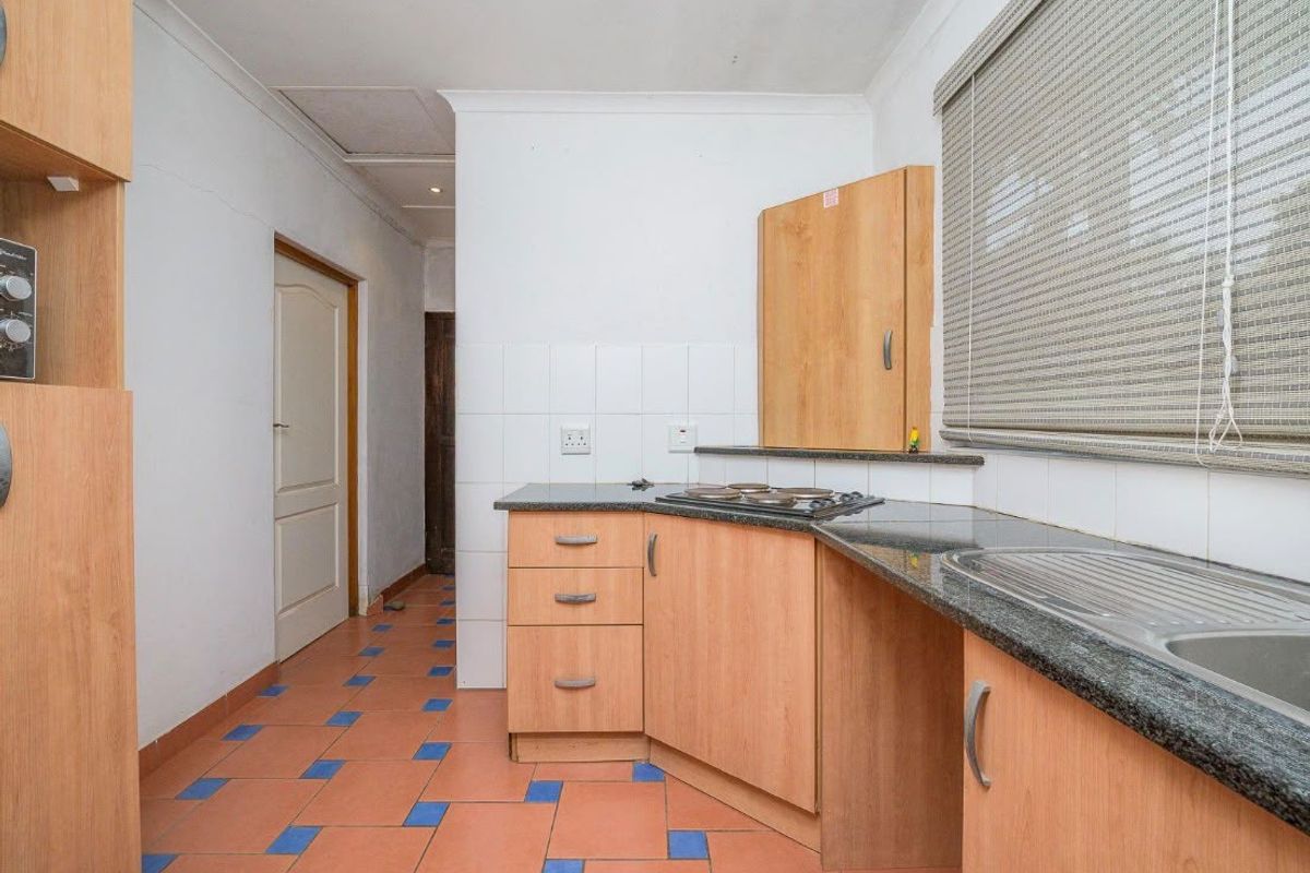 A functional kitchen featuring laminate cabinetry, granite countertops, a built-in hob, and a stainless steel sink with tiled backsplash.