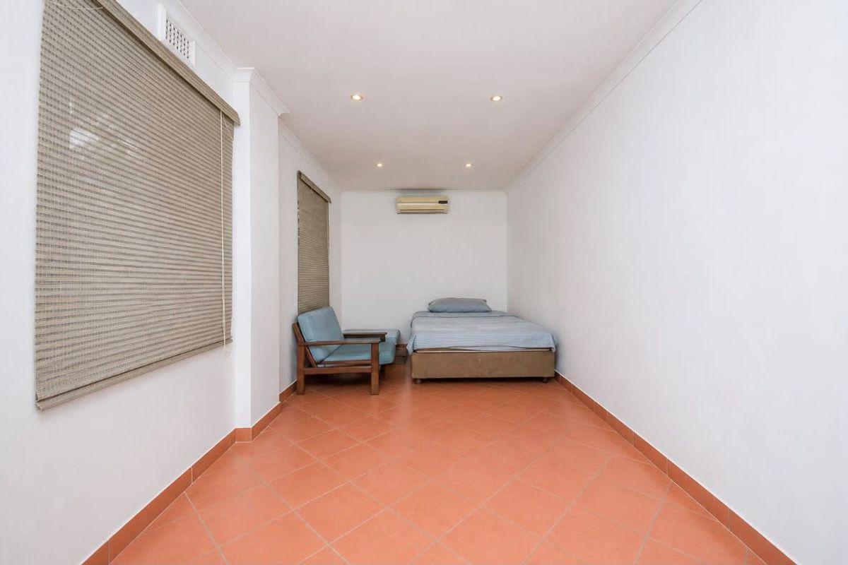A simple bedroom featuring ceramic tiled flooring, recessed downlighting, and a wall-mounted split-system air conditioning unit.