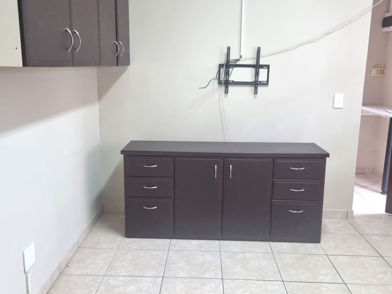 A living area featuring built-in dark cabinetry, ceramic floor tiles, and a wall-mounted TV bracket with visible wiring.