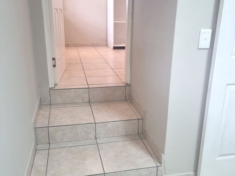 A tiled staircase leading to an adjacent room featuring built-in shelving and neutral wall finishes.
