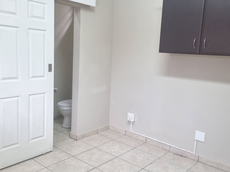 A functional laundry area featuring tiled flooring, wall-mounted storage cabinetry, and a sliding door leading to an adjacent bathroom.