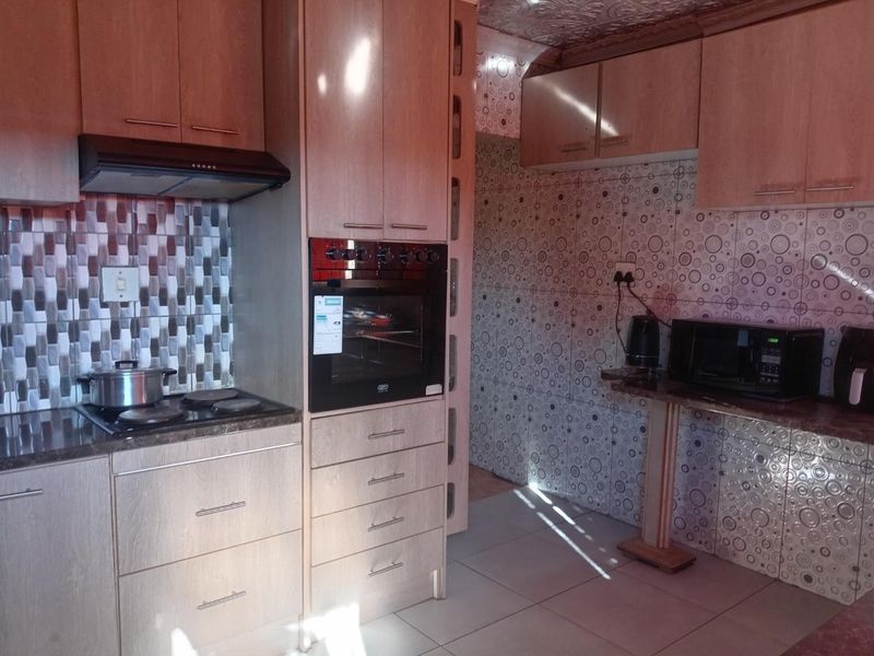 A functional kitchen featuring built-in cabinetry, an integrated oven, electric hob, extractor fan, and tiled finishes throughout.