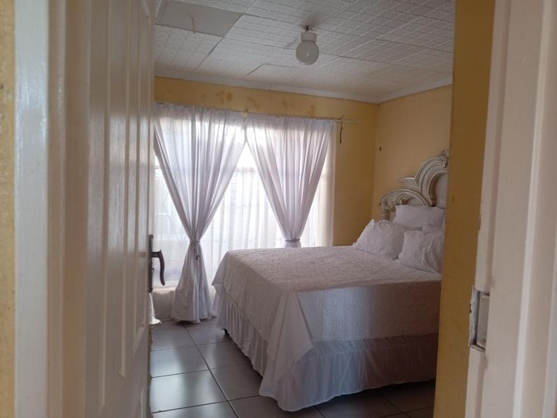 A bedroom featuring tiled flooring and ceiling tiles, requiring cosmetic updates to the wall paint and ceiling finish.