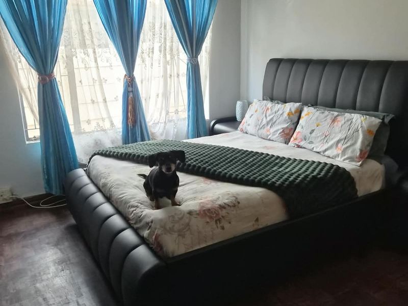 A bedroom featuring dark wood-look flooring and security burglar bars on the window.
