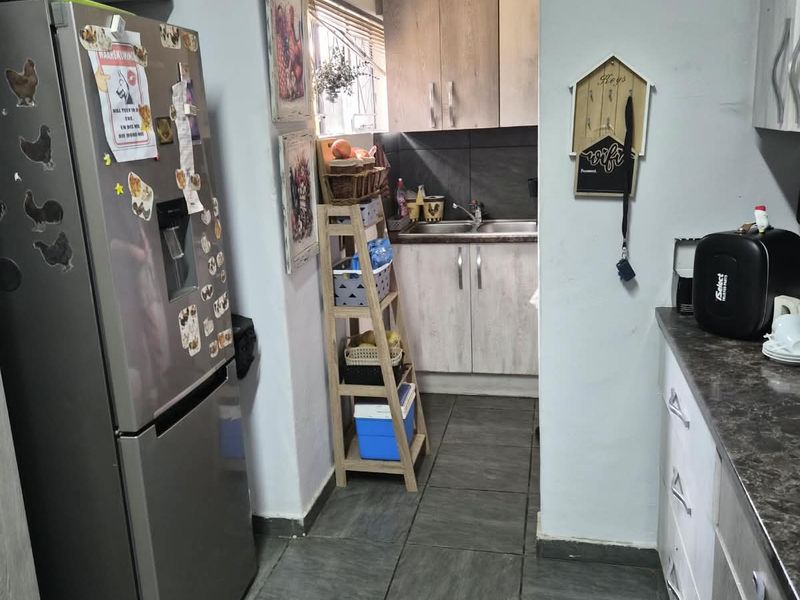A functional scullery area featuring built-in cabinetry, laminate countertops, a stainless steel sink, and tiled flooring, providing additional prep and wash-up space.