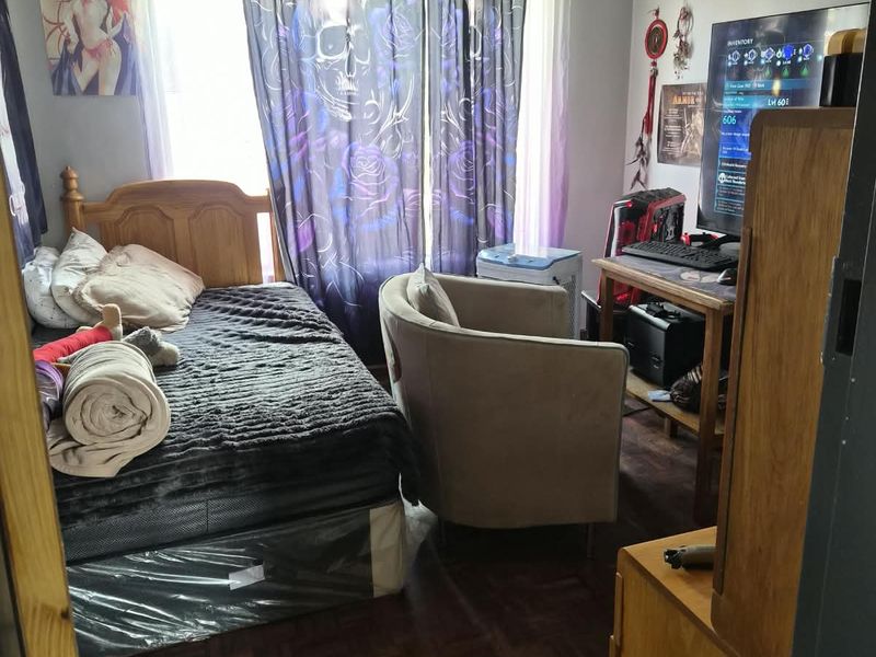 A bedroom featuring dark parquet flooring and ceiling ventilation, currently utilized as a multi-purpose living and sleeping space.