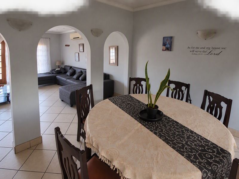 Open plan dining and living area featuring tiled flooring, arched architectural transitions, and wall-mounted climate control.