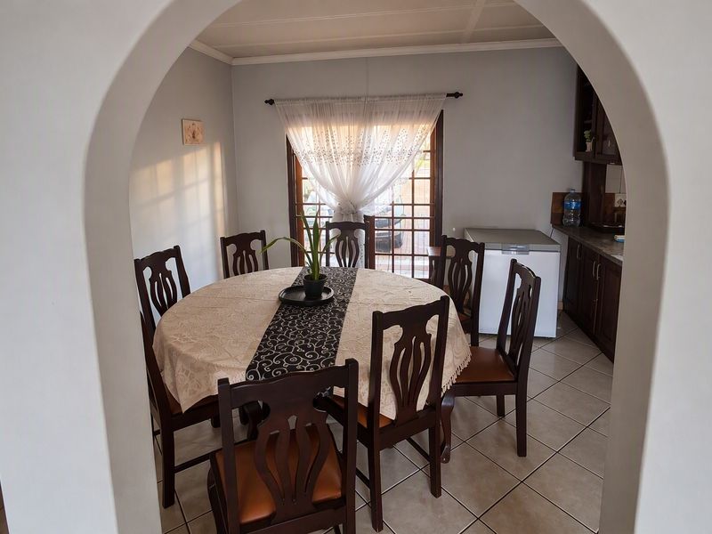 A dining area featuring tiled flooring and an arched entryway, with direct access to the kitchen and a sliding glass door leading outdoors.