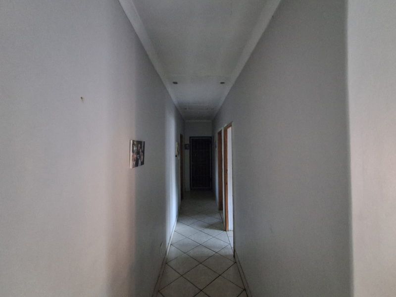 A functional hallway featuring tiled flooring and recessed ceiling lighting, providing access to multiple rooms within the home.
