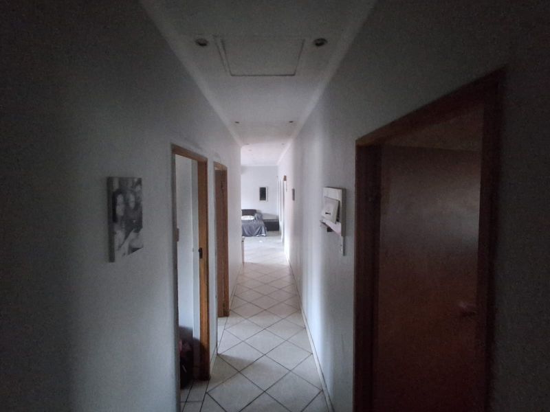 A functional hallway featuring tiled flooring, recessed downlighting, and access to multiple rooms via timber-framed doorways.