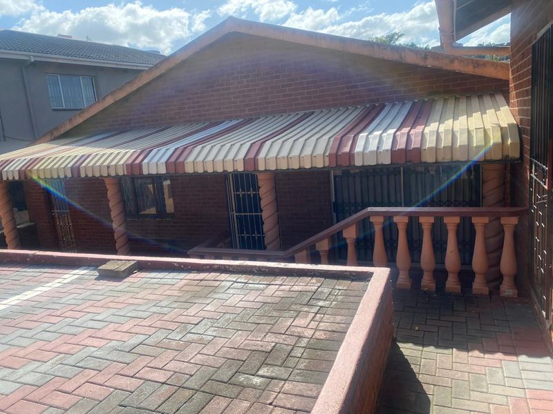 Front exterior view of the apartment building featuring a brick facade, paved driveway area, and a covered entrance with a striped awning.