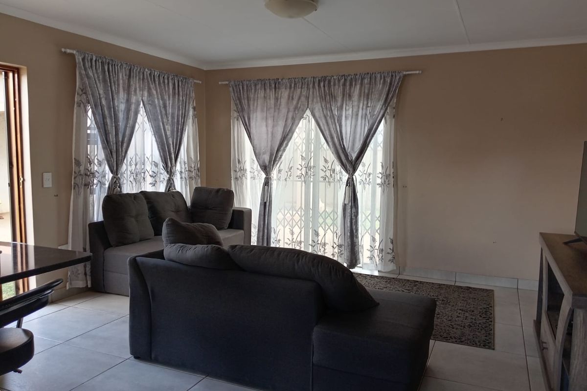 A living room featuring tiled flooring and sliding glass doors with security gates, providing access to the exterior.