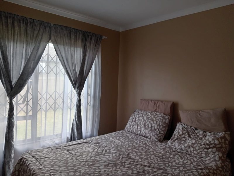 A bedroom featuring a window with a fitted security gate and decorative cornice detailing.