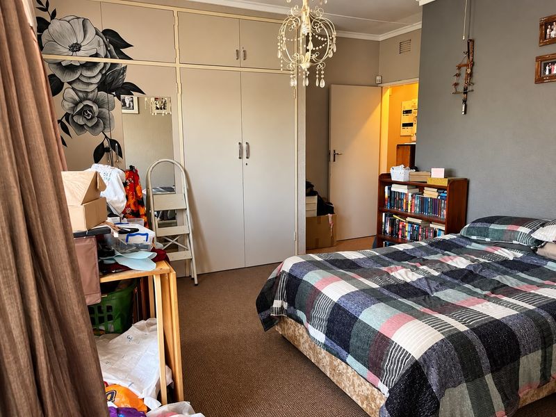 A bedroom featuring built-in cupboards, carpeted flooring, and a central light fixture, offering a functional space with potential for cosmetic updates.