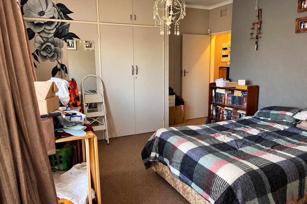 A bedroom featuring built-in cupboards, carpeted flooring, and a central light fixture, offering a functional space with potential for cosmetic updates.