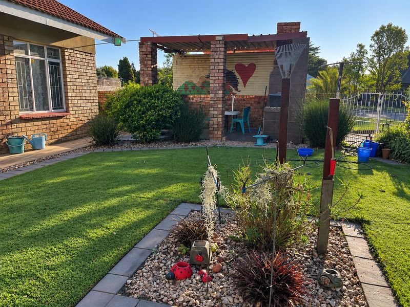 Rear garden featuring a brick-built pergola with an integrated braai area, established lawn, and paved garden borders.