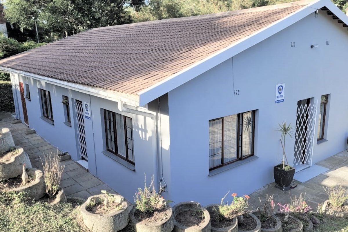 Rear view of the house featuring a tiled roof, paved walkways, and integrated concrete garden planters.