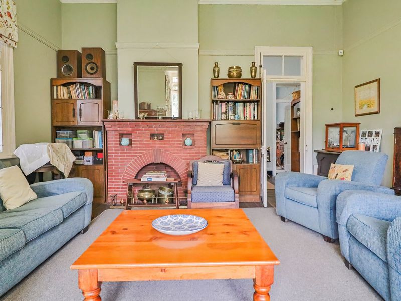 A traditional living room featuring a classic brick fireplace, picture rails, and timber-framed windows, offering a character-filled space with potential for modern updates.