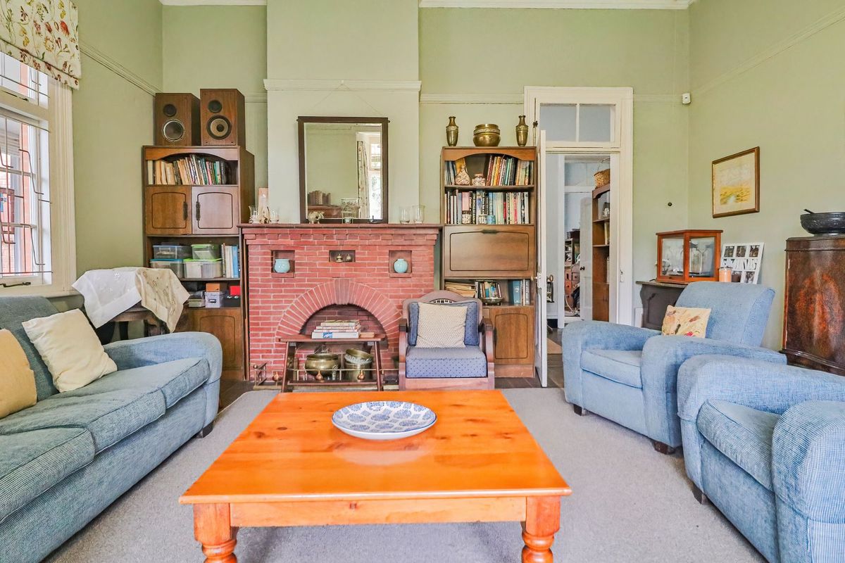 A traditional living room featuring a classic brick fireplace, picture rails, and timber-framed windows, offering a character-filled space with potential for modern updates.