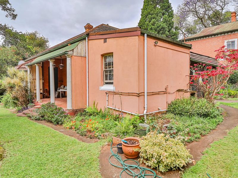 Rear view of the property featuring a covered patio, established garden, and exterior masonry walls with classic sash window detailing.