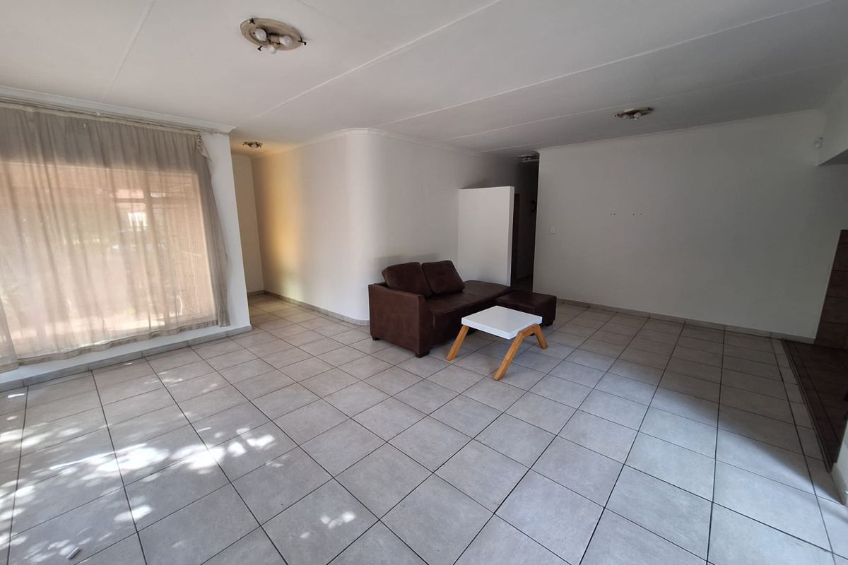 A spacious living area featuring neutral tiled flooring and simple ceiling lighting, offering a blank canvas for interior design updates.