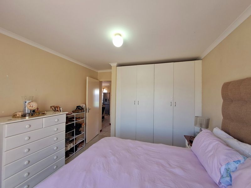A functional bedroom featuring built-in cupboards and neutral wall finishes, offering a comfortable and practical living space.