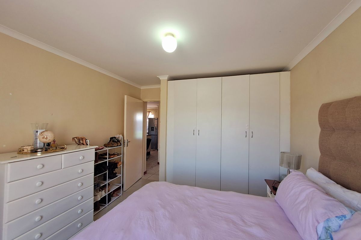 A functional bedroom featuring built-in cupboards and neutral wall finishes, offering a comfortable and practical living space.