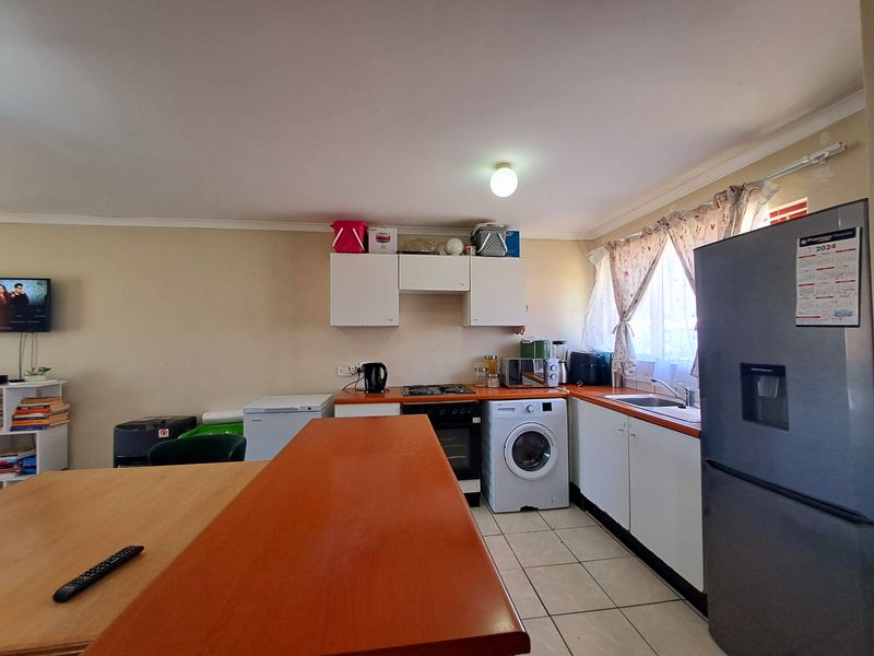 Functional kitchen featuring built-in cabinetry, laminate countertops, integrated oven and hob, and tiled flooring, offering a practical layout for daily meal preparation.