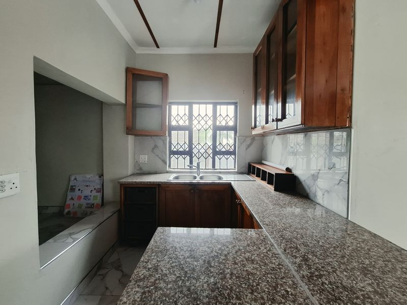 A functional kitchen featuring granite countertops, wooden cabinetry, and a double bowl sink, offering a solid foundation for a modern update.