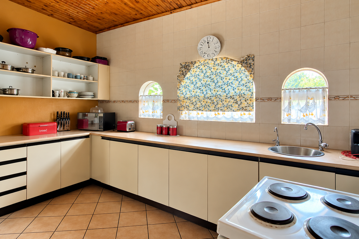 A functional kitchen featuring cream cabinetry, laminate countertops, a stainless steel sink, and a timber-paneled ceiling with tiled wall finishes.