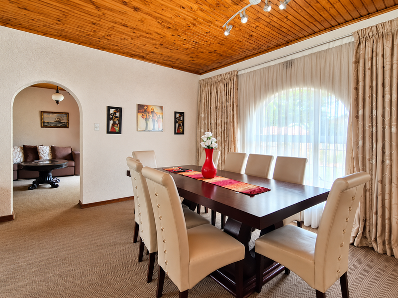 Dining room featuring a warm timber tongue and groove ceiling, an arched doorway leading to an adjacent living area, and a large arched window.