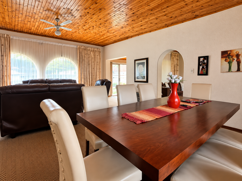 Spacious open-plan living and dining area featuring a warm timber tongue and groove ceiling, arched windows, and a classic arched transition between spaces.