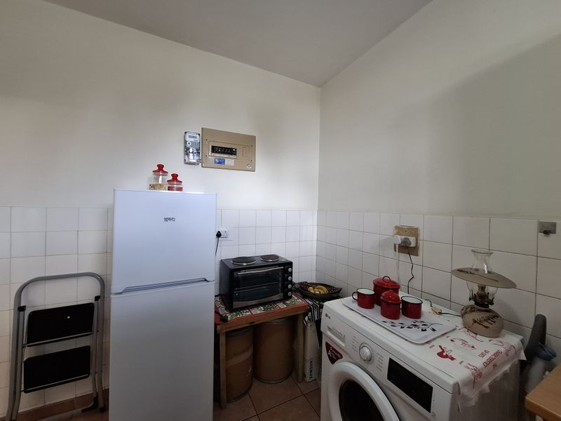 A functional laundry area featuring tiled splashbacks, tiled flooring, and a wall-mounted electrical distribution board.
