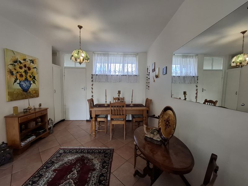 A dining room featuring tiled flooring, a large wall mirror, and a built-in cupboard, offering a functional space for meals.