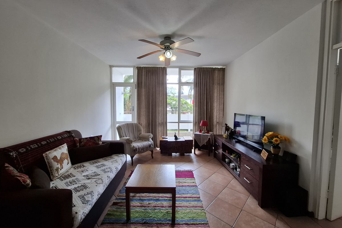 A living room featuring tiled flooring, a ceiling fan, and a sliding glass door providing access to an outdoor area.