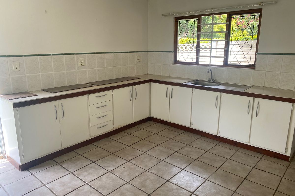 A functional, empty kitchen featuring white cabinetry, tiled splashbacks, and tiled flooring, offering a blank canvas for potential modern updates.